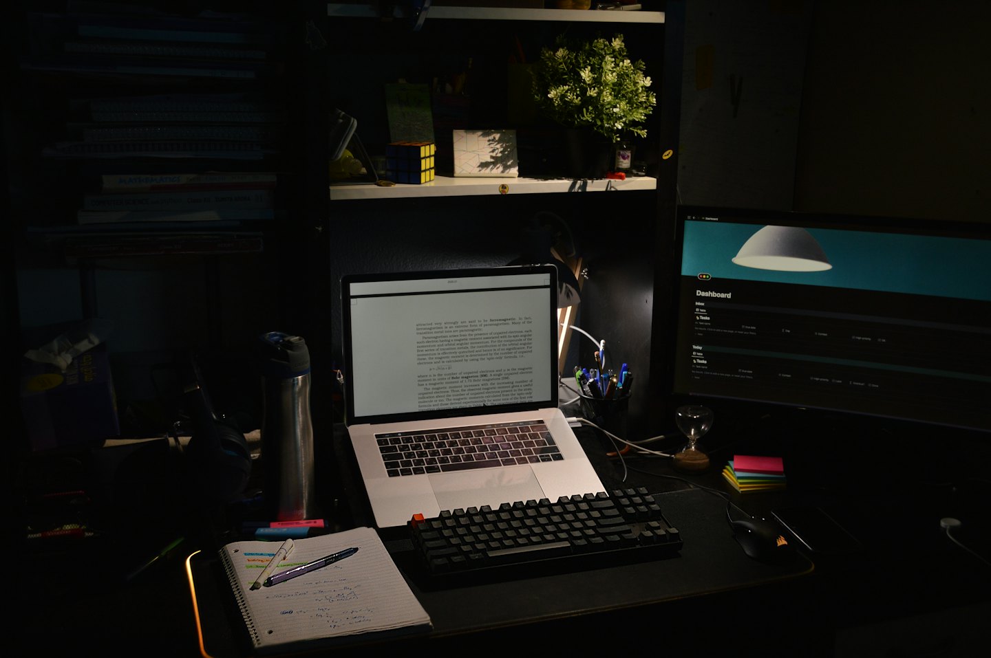 Laptop, monitor, and notebook on a home office desk.