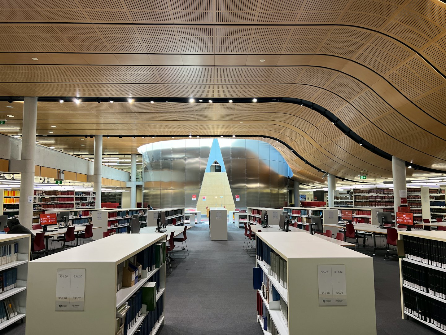 Students study at tables inside a spacious modern library.