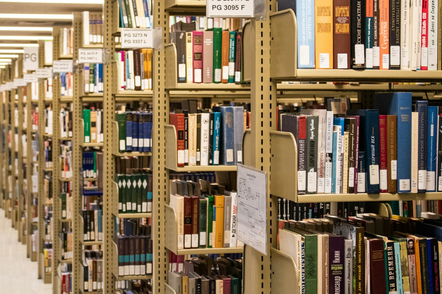 Rows of metal library shelves filled with many books.