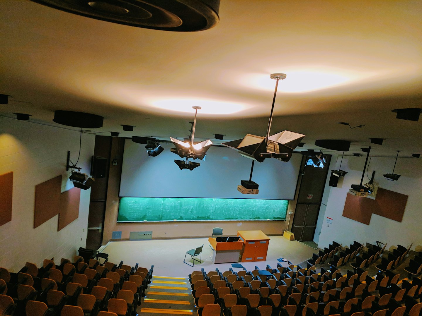 Empty lecture hall with rows of chairs and podium.