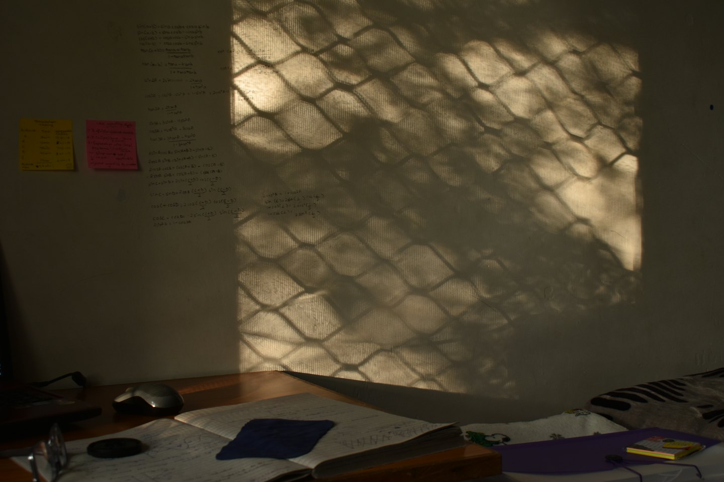 Mathematical formulas written on a desk notebook and wall.